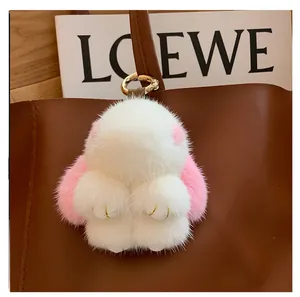 Detail of fluffy white bunny charm with pink ears hanging on a brown leather bag