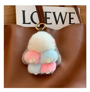 Close-up of a colorful faux fur bunny charm attached to a brown leather handbag handle