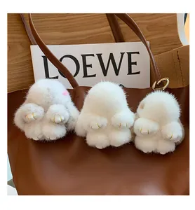 Detailed close-up of fluffy mink fur rabbit charms in white and grey on a leather bag