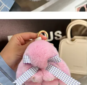 Detailansicht des rosa Plüsch-Hasenanhängers mit blau-weiß karierter Schleife an Handtasche