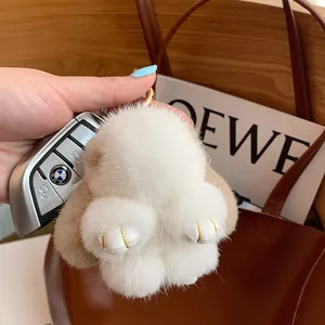 Plush mink fur rabbit keychain in white and beige tones hanging on a leather handbag
