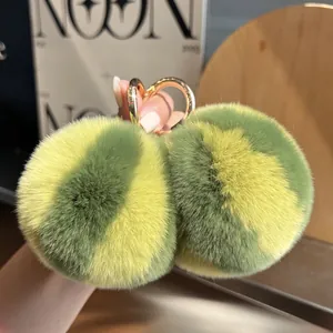 Detail of soft green and yellow striped rabbit fur pompom charm with golden ring