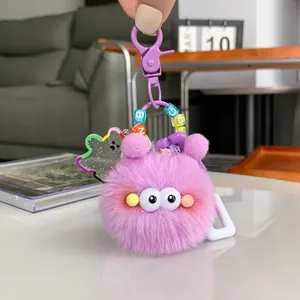 Cute purple plush monster keychain with big eyes and colorful letter beads on a cozy background