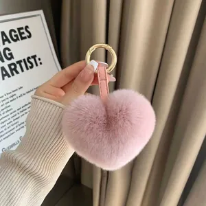 Detail of pink heart-shaped faux fur keychain with leather strap and golden clasp