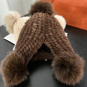 Thick knitted winter hat with large fur pom-pom in dark brown and off-white colors