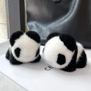 Detailed view of two mink fur panda charms on a black handbag, showing premium texture