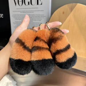 Detailed view of three striped rex rabbit fur tiger tail keychains with gold metal rings