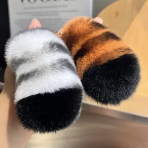 Close-up of fluffy striped tiger tail keychains with gold clasps in hand