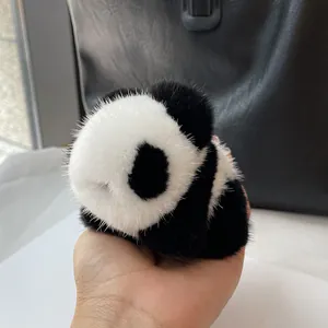 Detail view of a fluffy panda plush keychain made of premium mink fur being held by hand