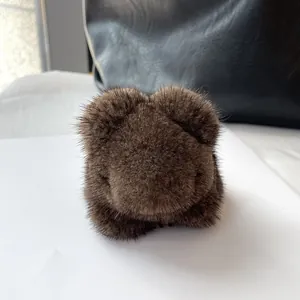 Close-up of brown mink fur panda keychain with soft plush texture on a leather bag