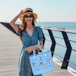 Light blue EVA beach tote bag with summer charms in an outdoor coastal setting