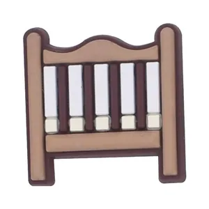 Detalle de adorno de PVC para zuecos con forma de cuna de bebé en color marrón y blanco