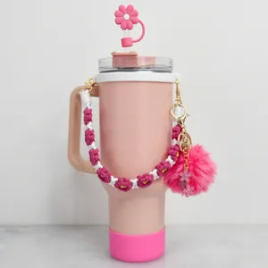 Détail du gobelet rose avec protège-paille fleur, poignée tissée et porte-clés pompon