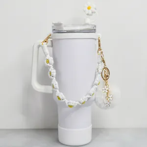Détail de gobelet isotherme blanc avec couvercle marguerite et sangle fleurie tissée