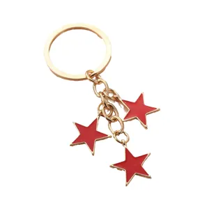 Porte-clés minimaliste doré avec trois pendentifs étoiles rouges sur fond blanc