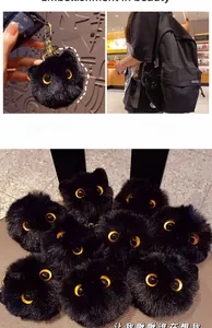 Detail of soft black plush cat keychain with yellow eyes and gold metal clip