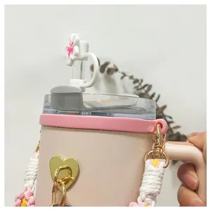 Close-up of Stanley tumbler straw cover, woven handle and gold heart pendant set