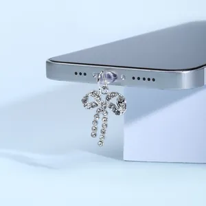 Détail du bouchon anti-poussière avec nœud argenté et strass brillants sur le téléphone