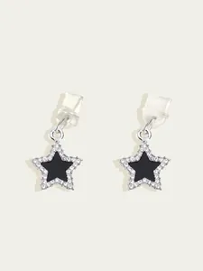 Détail de boucles d'oreilles étoiles avec centre noir et bordure en cristaux pavés