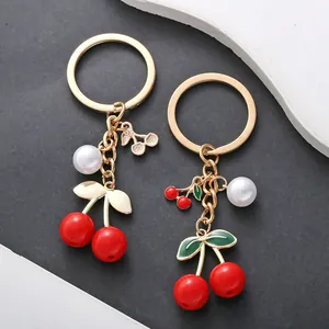 Red cherry and pearl keychain with gold-tone alloy ring and green enamel leaf detail