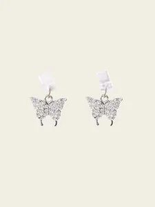 Gros plan de boucles d'oreilles papillon en argent avec cristaux et fermoirs silicone