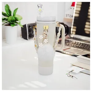 Cream tumbler with 26 alphabet charms, floral chain, and straw cover in desk setting