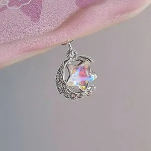 Vue macro d'un pendentif lune argentée et étoile holographique aux reflets brillants