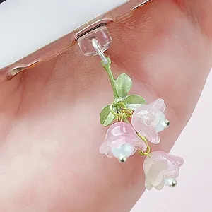Détail du bouchon anti-poussière muguet avec pétales dégradés roses et feuilles vertes