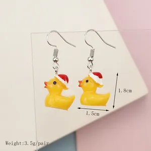 Cute yellow resin duck earrings with red Christmas hats on a pink and white background