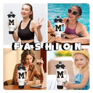 Détail des accessoires pour tasse Stanley avec noeud noir pailleté et breloque lettre M