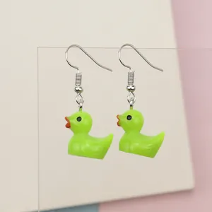 Close-up of cute neon green resin duck earrings with red beaks and silver hooks