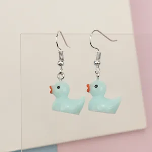 Close-up of light blue resin duck earrings on a display stand with a soft pastel background