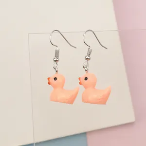 Close-up of cute peach pink resin duck earrings with detailed orange beak and silver hooks