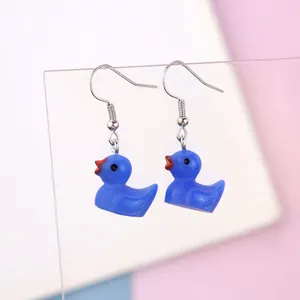 Detail shot of cute blue resin duck drop earrings with silver hooks on acrylic stand