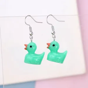 Detail of cute mint green resin duck earrings with silver hooks on an acrylic stand