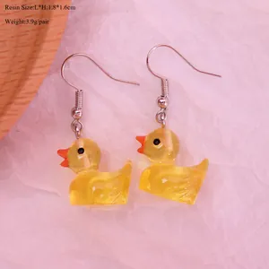 Detail showing size dimensions and resin texture of yellow duck dangle earrings