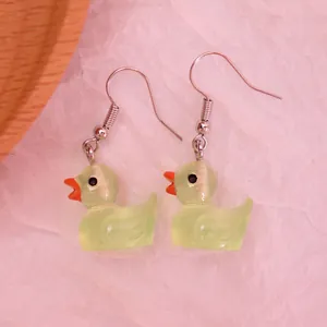 Detail showing cute resin duck earrings in translucent light green with metal hooks
