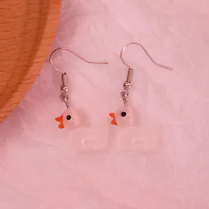 Macro detail of cute white resin duck earrings with orange beaks and silver hooks