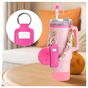 Pink keychain lip balm holder with pom-pom charm and cherry blossom straw cover accessory