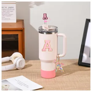 Pink 40oz insulated tumbler with letter A sequin patch, straw cover, and charm accessories