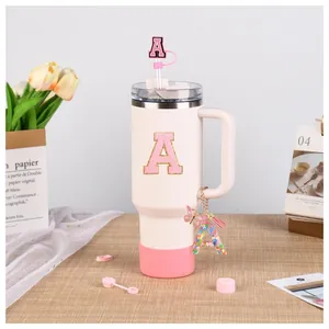 Detail of white 40oz tumbler with pink letter A embroidery, straw cover and handle charm