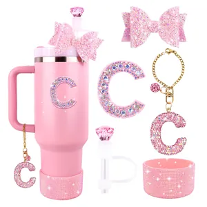 Pink Stanley cup accessory set with glitter bow, straw cover, and rhinestone letter charm