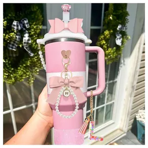 Pink tumbler with handle featuring glitter base, leather bow, and personalized letter charms