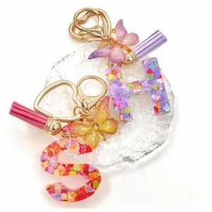 Dettaglio portachiavi in resina con cuori glitterati, farfalla e nappe colorate vivaci