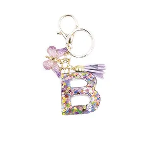 Resin letter B keychain with purple tassel, butterfly, and colorful floral sequins