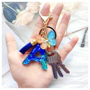 Porte-clés lettre A en résine avec paillettes bleues, papillon et pompon bleu assorti