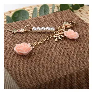 Close-up of pink resin roses with white faux pearls and golden leaf charm keychain