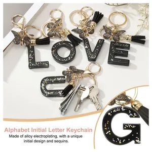 Porte-clés lettre en résine avec paillettes dorées, pompon et papillon chic