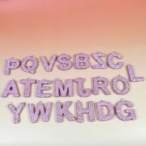 Gros plan de breloques alphabétiques en strass roses avec crochets en métal doré