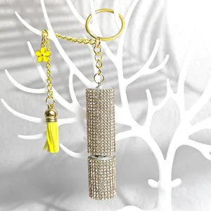Detail of luxury rhinestone perfume bottle keychain with yellow tassel and flower